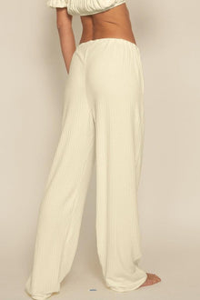 Cream ribbed drawstring pants with wide legs and side pockets shown on model from waist down.