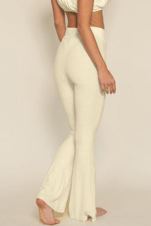 Cream ribbed flare pants with high waist and cutout back detail worn by model.
