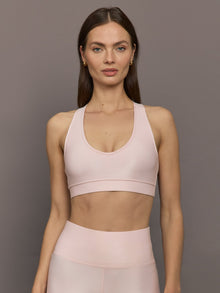 Model wears a v neck baby pink bra in a liquidy takara shine finish. 