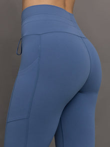 Model wears a periwinkle blue buttery soft pair of leggings with pockets and drawstring waist, perfect for all activities. 