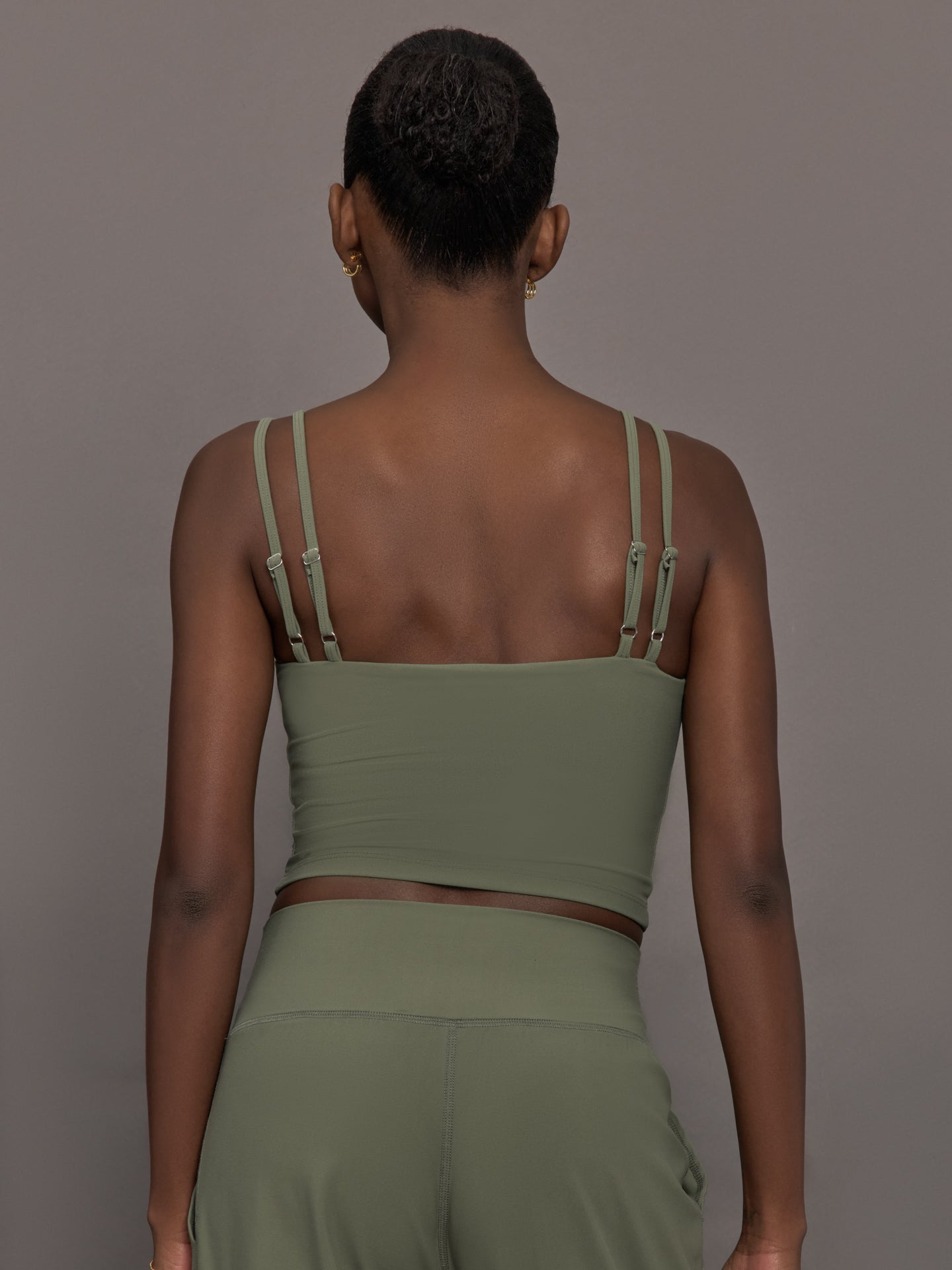 Model wears an army green tank top with double straps. 