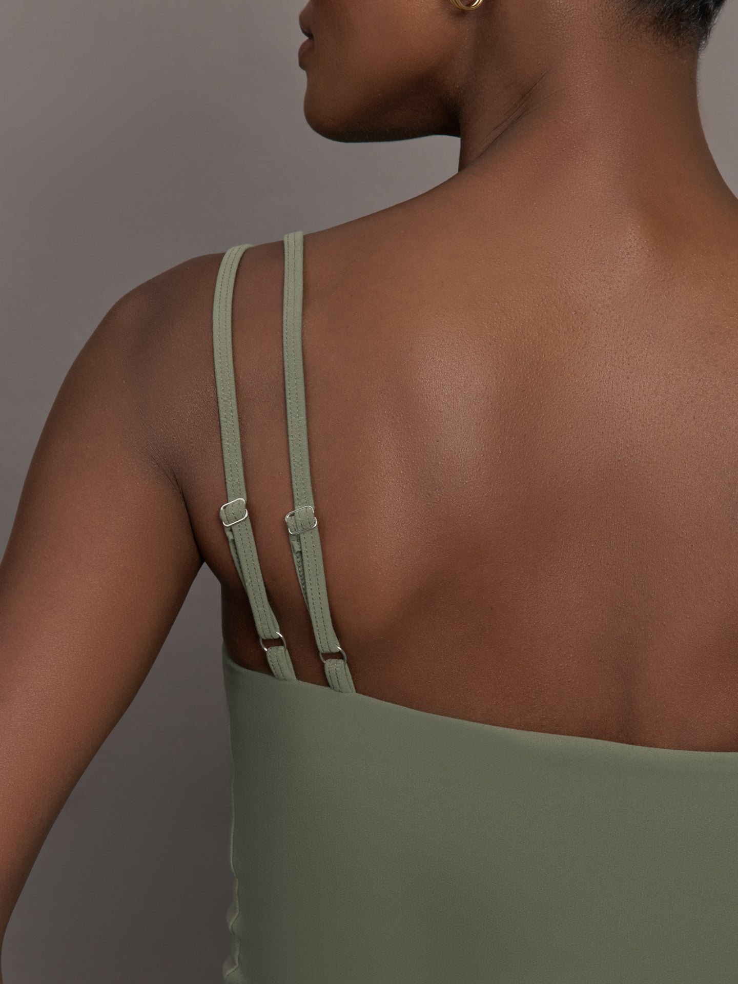 Model wears an army green tank top with double straps. 