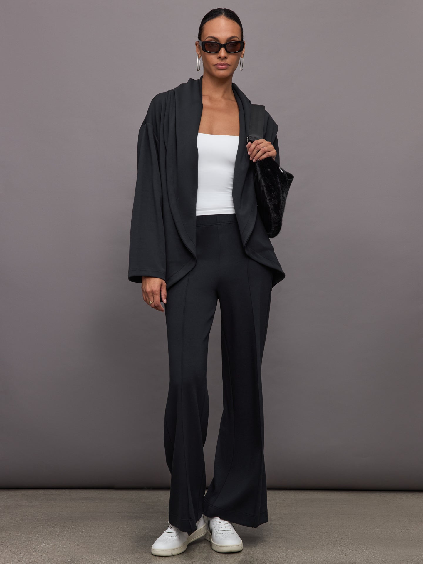 Model wears black open-front cardigan with a loose, draped fit, wide bell sleeves, and side pockets.