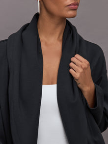 Model wears black open-front cardigan with a loose, draped fit, wide bell sleeves, and side pockets.