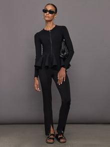 Model wears black long-sleeve zip-up sweater with a fitted bodice and flared peplum hem.