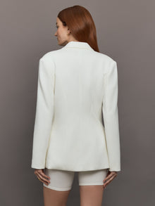Model wears the white double-breasted blazer in Scuba, with a tailored fit, and a smooth, contoured finish.