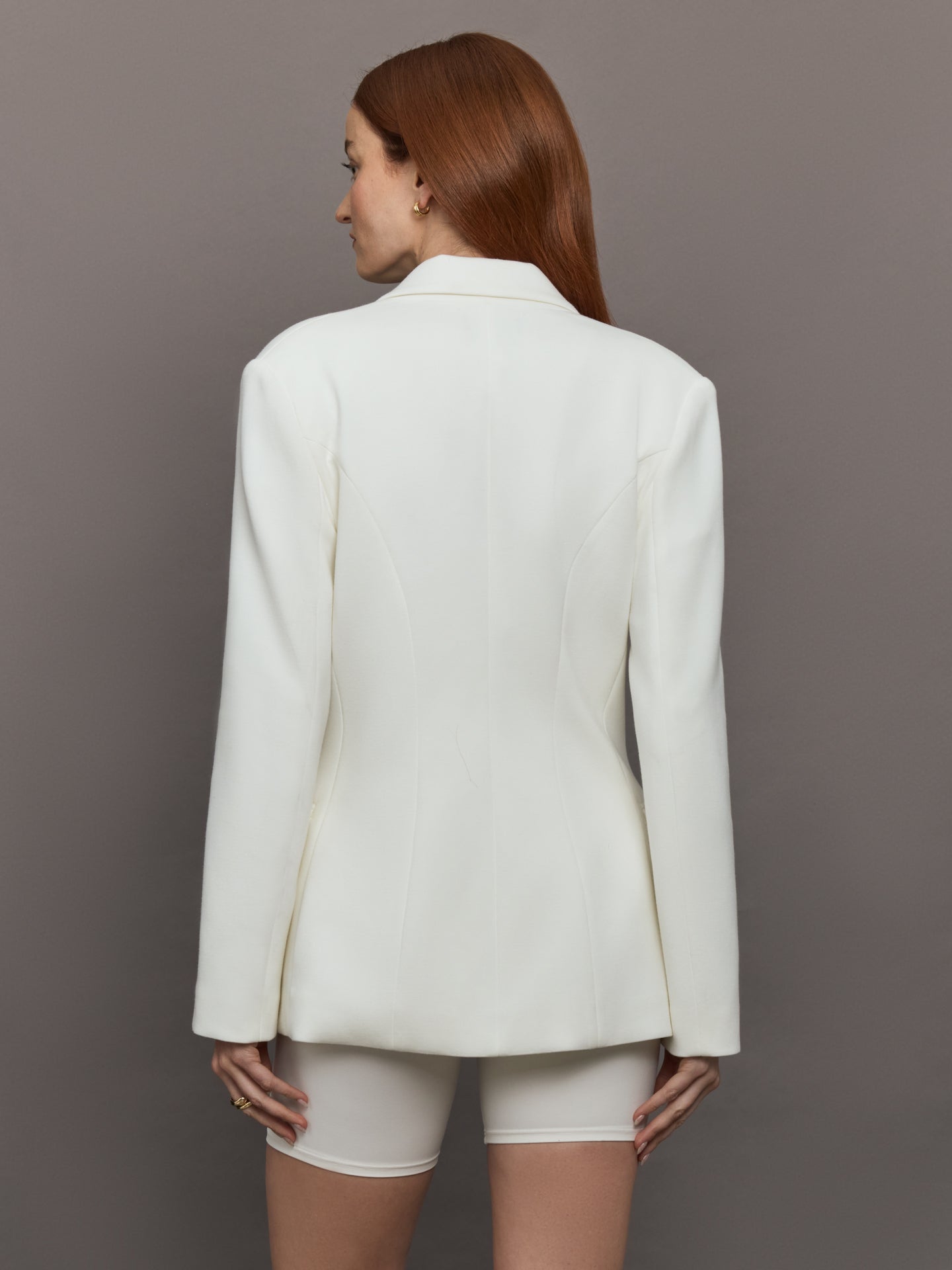Model wears the white double-breasted blazer in Scuba, with a tailored fit, and a smooth, contoured finish.