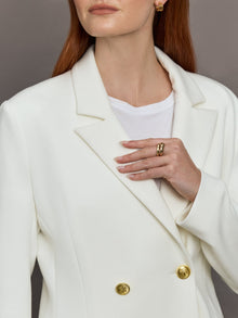 Model wears the white double-breasted blazer in Scuba, with a tailored fit, and a smooth, contoured finish.