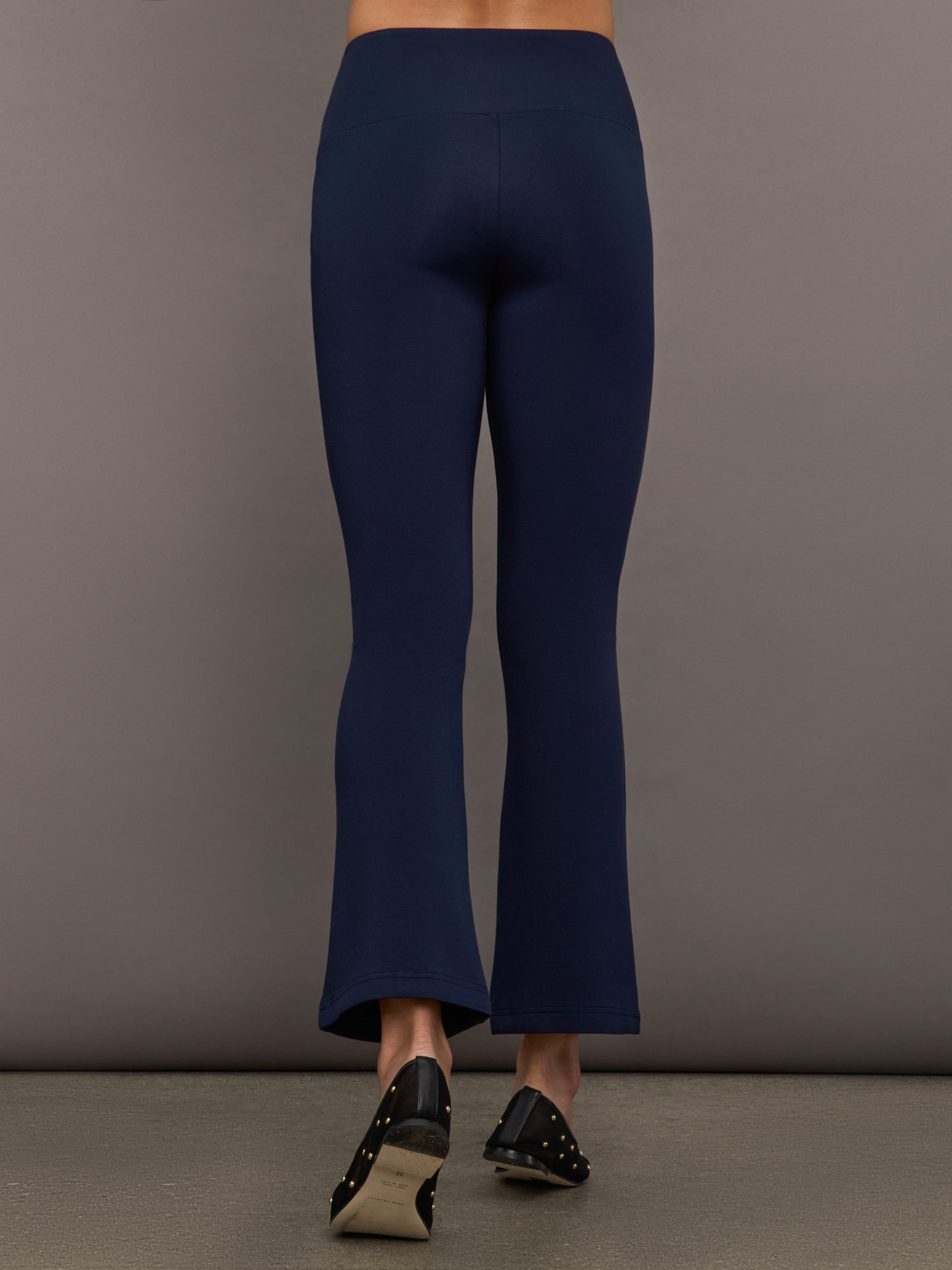 Navy high-rise pants with a fitted, sculpting silhouette through the hips and thighs, flaring out subtly at the hem.