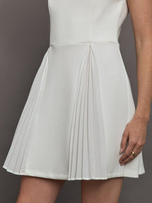 Model wears a white sleeveless tennis dress with pleating below the waist.