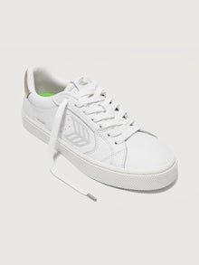 White sneaker with metallic gold heel and leaf logo on side. 