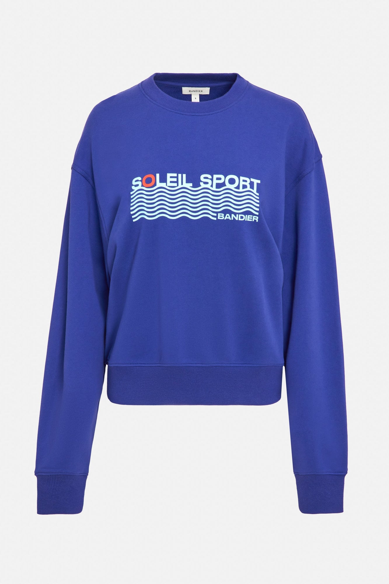 A royal blue crewneck sweatshirt with the lettering "Soleil Sport" across the chest with wavey lines below and "Bandier" in the bottom right corner. 