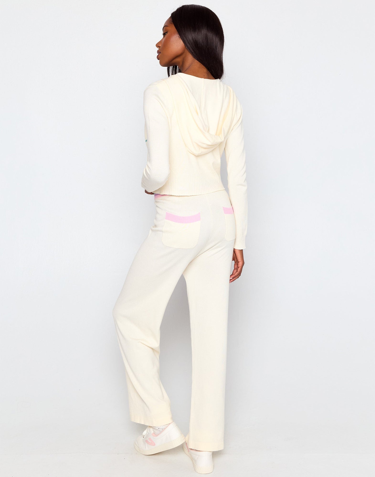 Person wearing a light-colored outfit with a plain background
