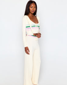 Woman wearing a white outfit with colorful stripes on a plain background