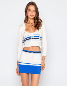 Woman wearing a white and blue outfit with a striped top and skirt on a plain background