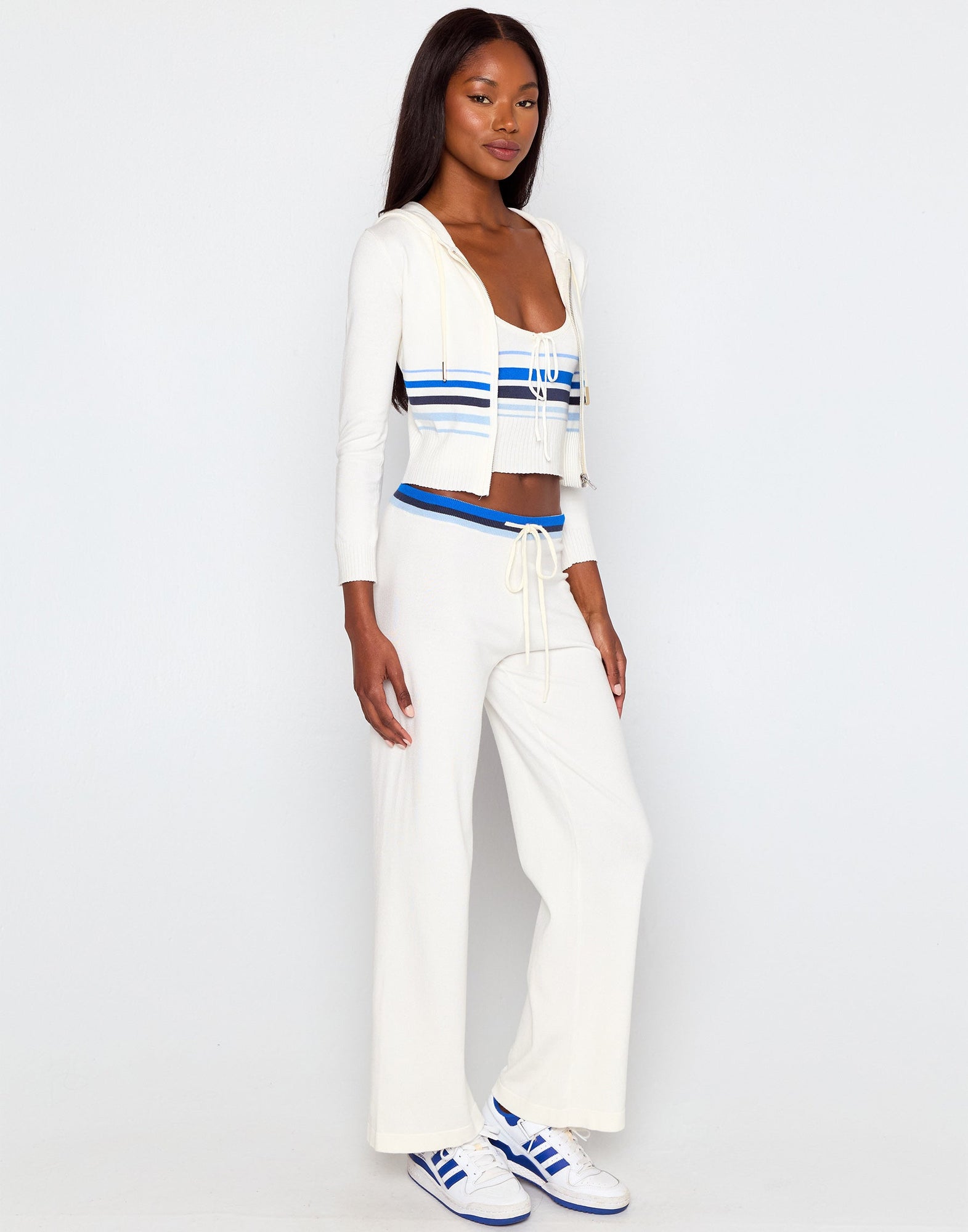 Woman wearing a white outfit with blue accents on a plain background