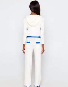 Person wearing a white outfit with blue accents on a plain background