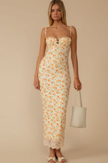 Cream slip dress with orange petal print, sweetheart neckline, lace trim hem, and thin shoulder straps.