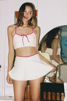 Cream racerback sport top with raspberry binding and tie-front detail on model.