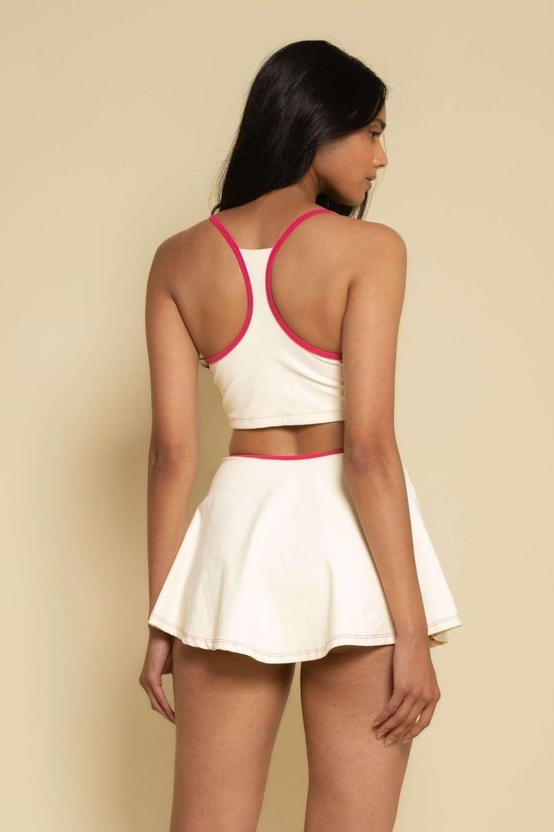 Cream racerback sport top with raspberry binding and matching waistband, shown from back.