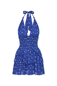 Low-cut navy blue convertible halter dress with hand-painted star print all over and a smocked waist, ties in a generous bow at the neck and can be crossed at front with a flared skirt with two ruffled tiers.