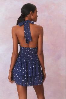 Low-cut navy blue convertible halter dress with hand-painted star print all over and a smocked waist, ties in a generous bow at the neck and can be crossed at front with a flared skirt with two ruffled tiers.