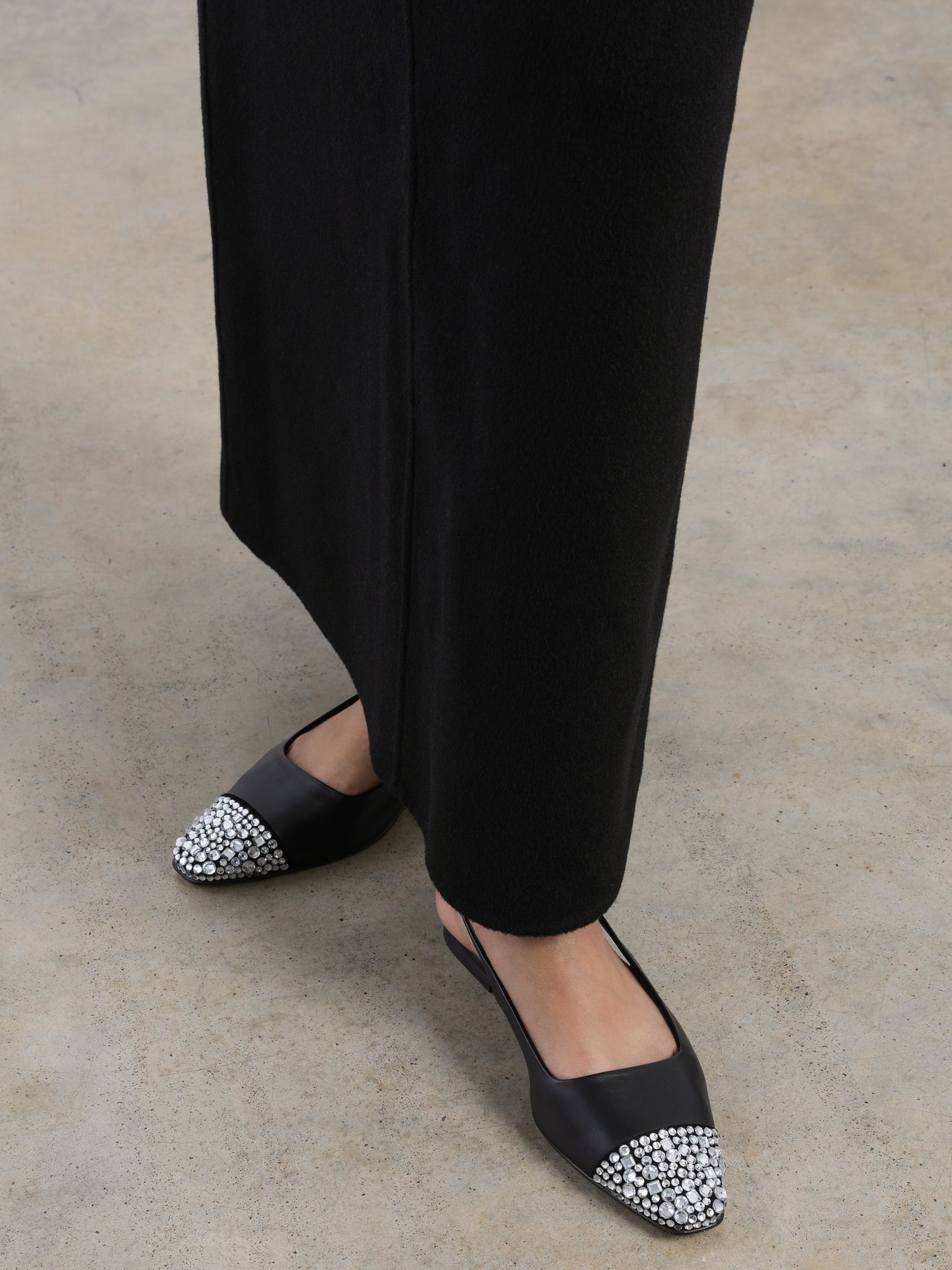 Black leather slingback flat with a sharp square-toe and crystals on the cap.