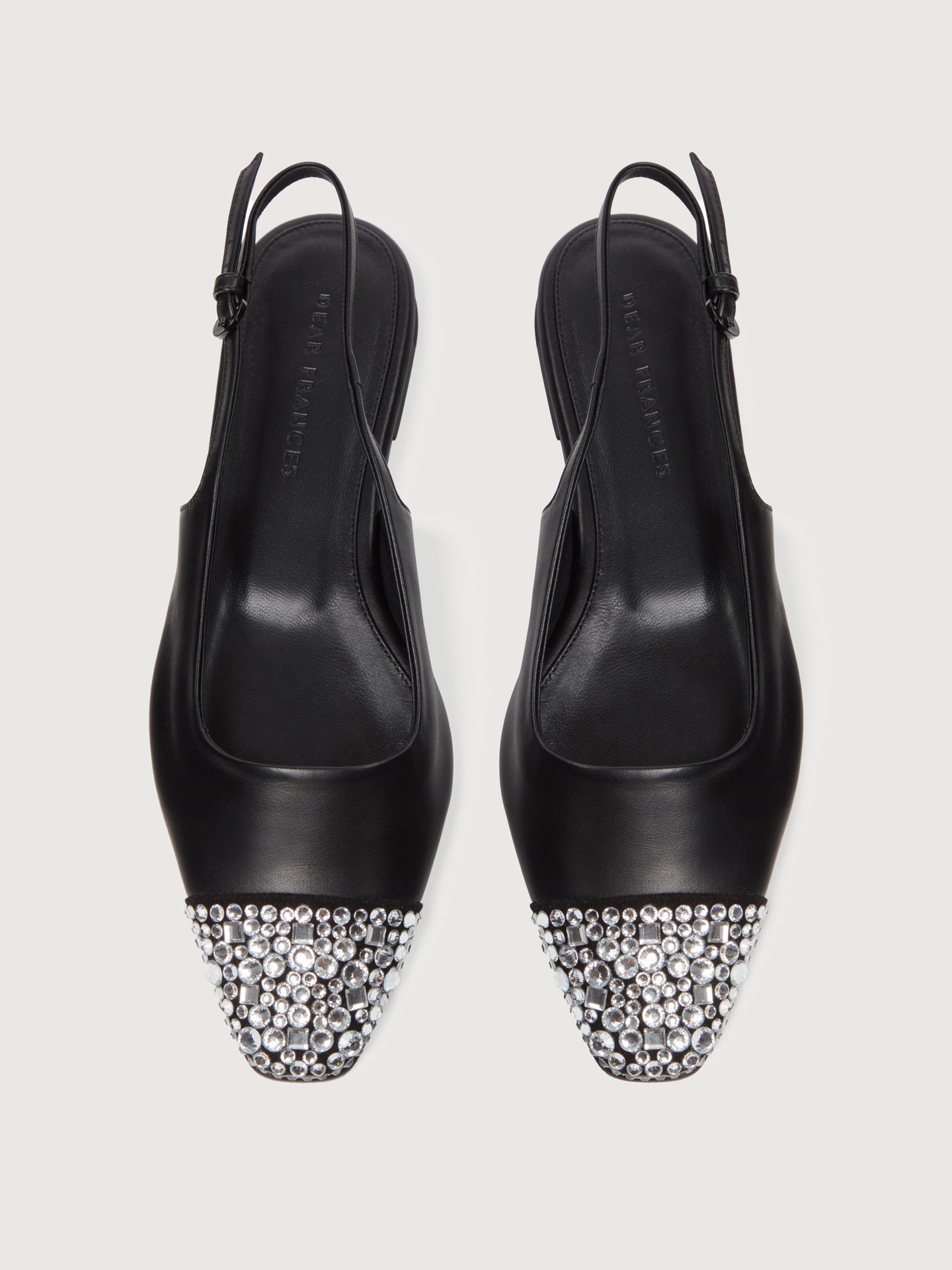 Black leather slingback flat with a sharp square-toe and crystals on the cap.