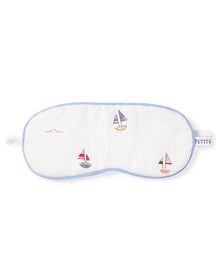 The Kids Twill Sleep Mask in Bateau by Petite Plume is a white luxury mask with blue trim, featuring small embroidered sailboats and waves. A PETITE tag on the right side makes it perfect for a matching set.