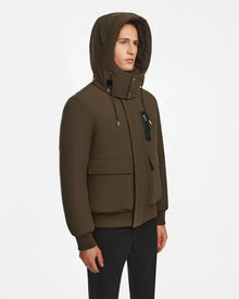 Model wears the Rudsak ASH - 6124599 Army mens down bomber jacket in dark olive, with front pockets, ribbed cuffs, and black drawstrings, styled with black pants against a white background for an urban look.