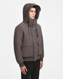 A person wearing the Rudsak ASH - 6124599 Grey mens down bomber jacket and black pants stands against a plain white background.