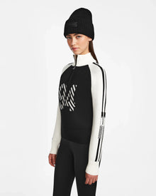 A woman wears the Rudsak FANNY - 8524506 Black knit pullover sweater and hat, ideal for winter layering.