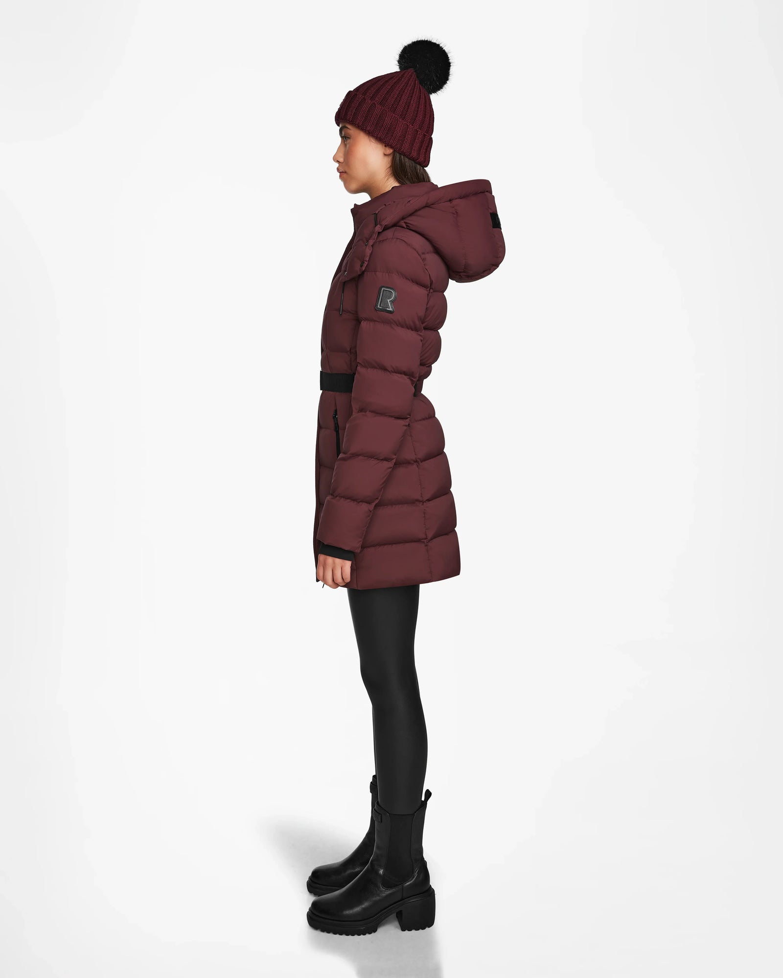 A woman in the Rudsak FRIDA M - L124524 Wine, a quilted down jacket with a removable hood.