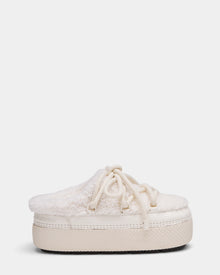 The Rudsak HARRIET - 8224519 Iceland is a cream women’s slipper mule featuring a thick rubber sole, faux shearling upper, lace-up detail, and cozy textured finish, shown from the side on a plain white background.
