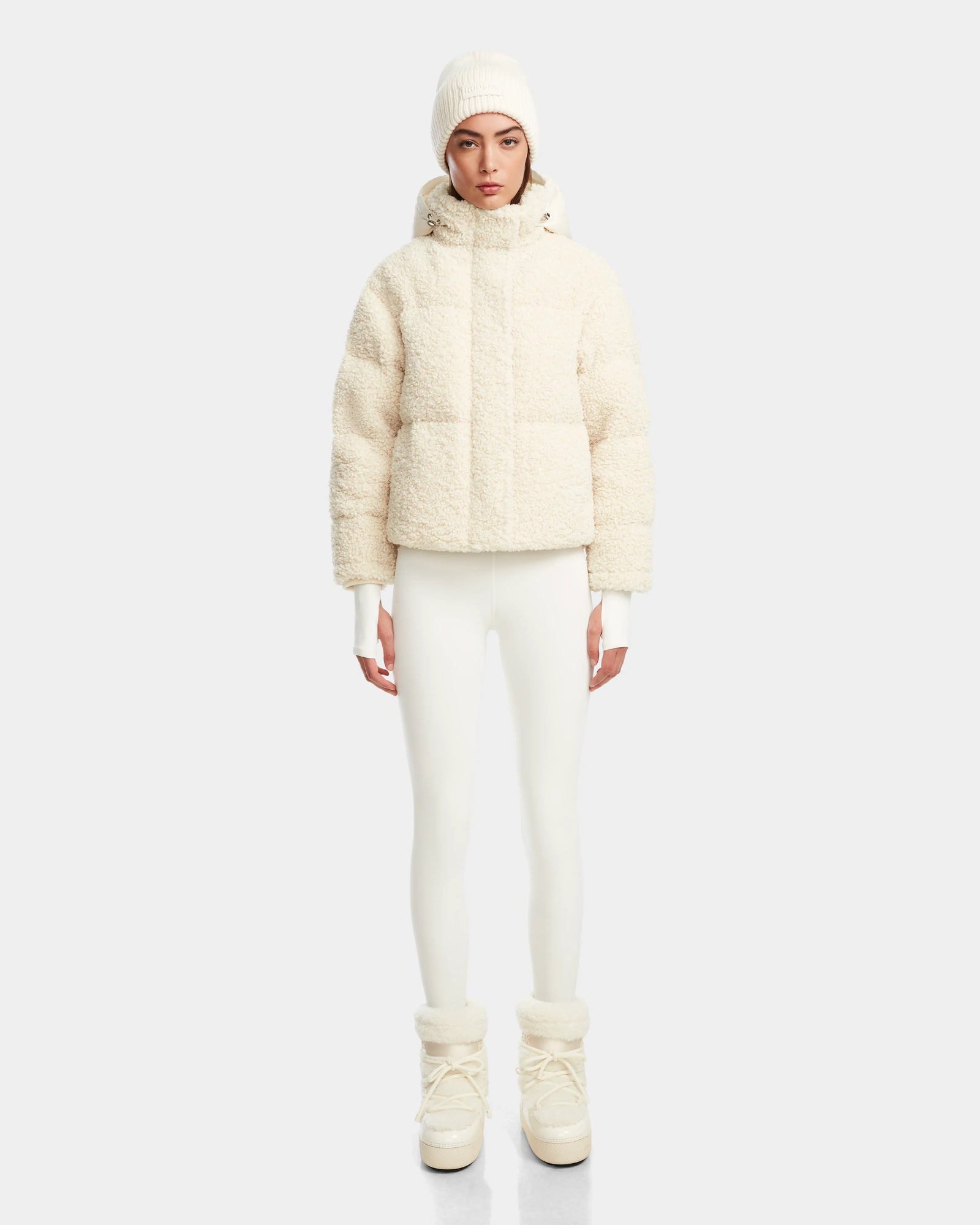 A person in an all-white winter outfit, featuring the Rudsak IKSA - 8124706 Iceland RDS-certified down jacket, fitted pants, knit hat, gloves, and snow boots, stands facing forward against a plain light background.