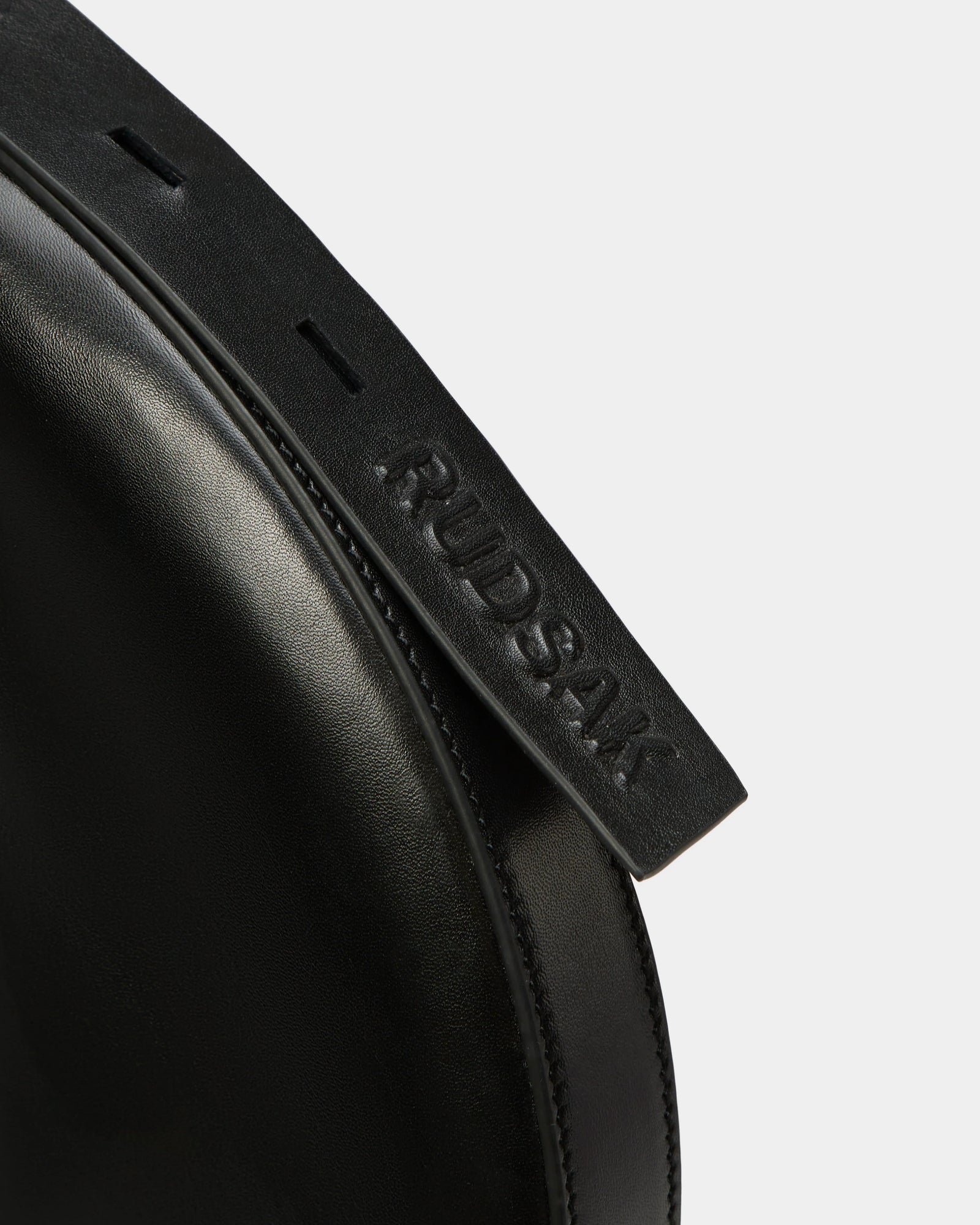 Close-up of the Rudsak LANISSA - 8324505 Black leather hobo bag, highlighting its black strap embossed with the brand name, set against a plain white background.