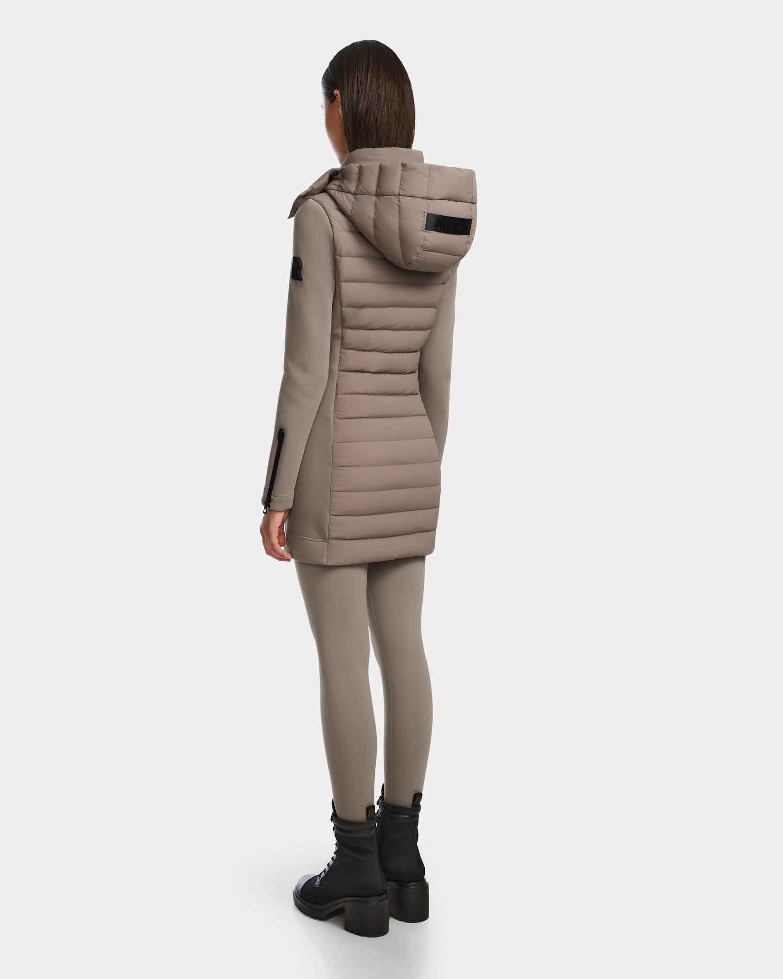 A person wearing the Rudsak MERINA M - 8124030 Cement women’s light hooded jacket, matching leggings, and black chunky boots stands facing away against a white background.