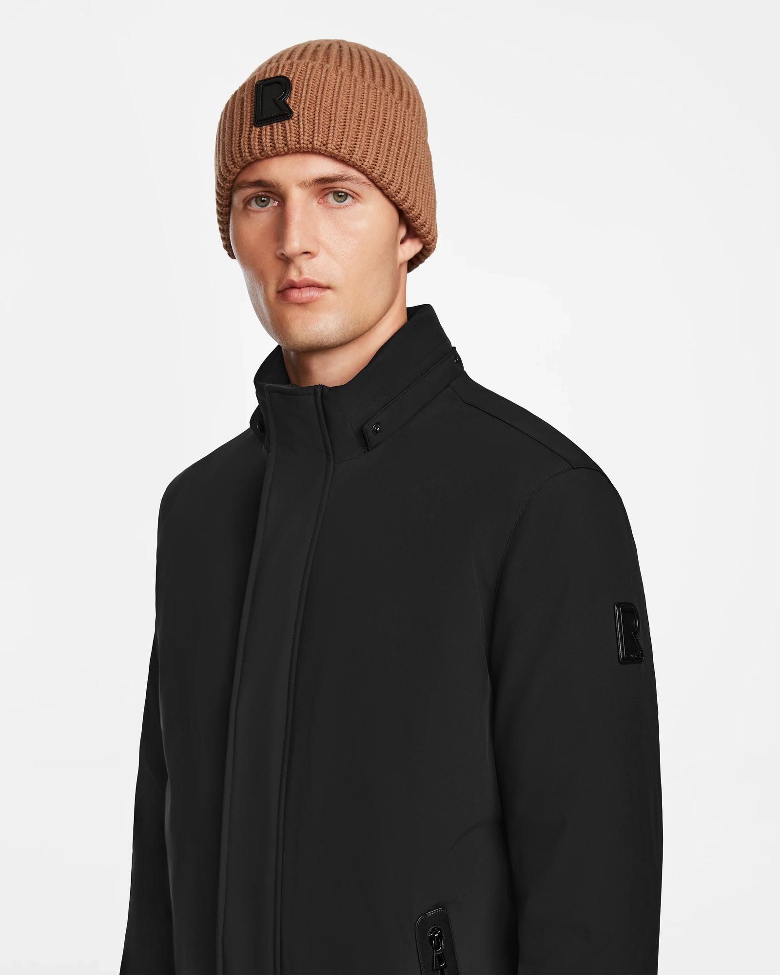 A man wearing the Rudsak NATAN - M124519 Black men’s parka with down fill insulation and a brown beanie.