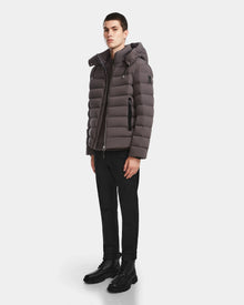 A young man stands facing forward, wearing the Rudsak NAVAN - 6124551 Grey mens quilted down puffer jacket with RDS-certified down, paired with black pants and black boots, against a plain white background.