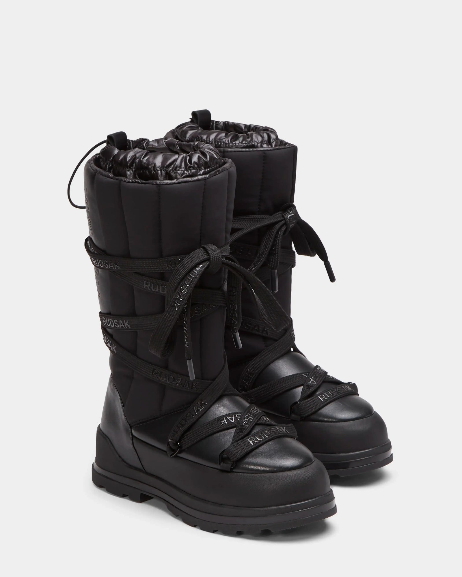 RODIN - 8224502 Black by Rudsak: tall black womens winter boots with thick anti-slip soles, lace-up fronts, quilted uppers, and branded straps for stylish support and comfort in cold weather.
