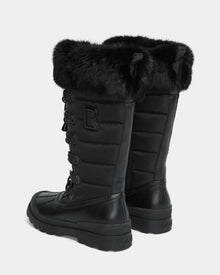 The Rudsak WINDY - L224507 Black is a pair of tall women’s winter boots featuring faux fur trim, quilted sides, thick rubber soles, decorative laces, a side zipper, and an 