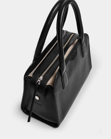 The YASMINA - 8324527 Black by Rudsak is a womens leather tote bag with sturdy double handles and a silver zipper, shown from above on a white background. Its interior is lined with light-colored fabric.