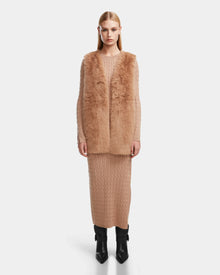 A woman wearing the Rudsak YOLANDA - 8124790 Camel faux fur vest and skirt, cinched with a vegan leather belt—an elegant addition to any fall or winter wardrobe.