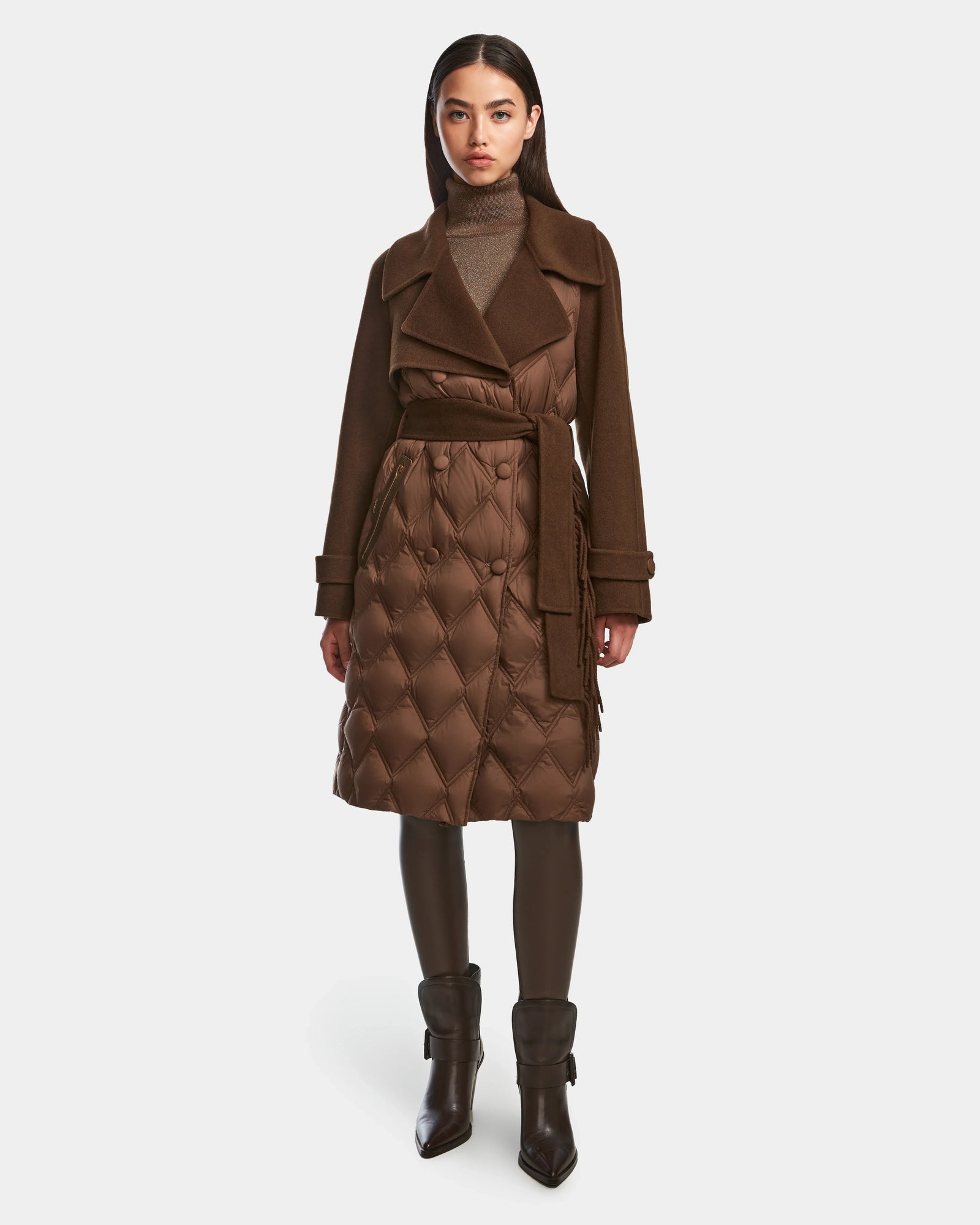 A woman faces forward against a white background wearing the Rudsak ZOE - 8124711 Mocha womens long trench coat, styled with a brown turtleneck, brown leggings, and heeled ankle boots.