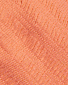 Close-up of a textured orange-colored fabric surface