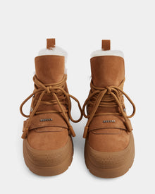 A top view of Rudsak ALEXEY - L225025 Tan women's suede winter boots in brown, with thick rubber soles, white wool lining, and large matching laces. The Rudsak logo is visible on each boot.