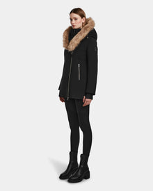 A person wearing the Rudsak AURORE - L123561 Black/Natural womens down parka with a large fur trim, black leggings, and black boots stands against a plain white background.