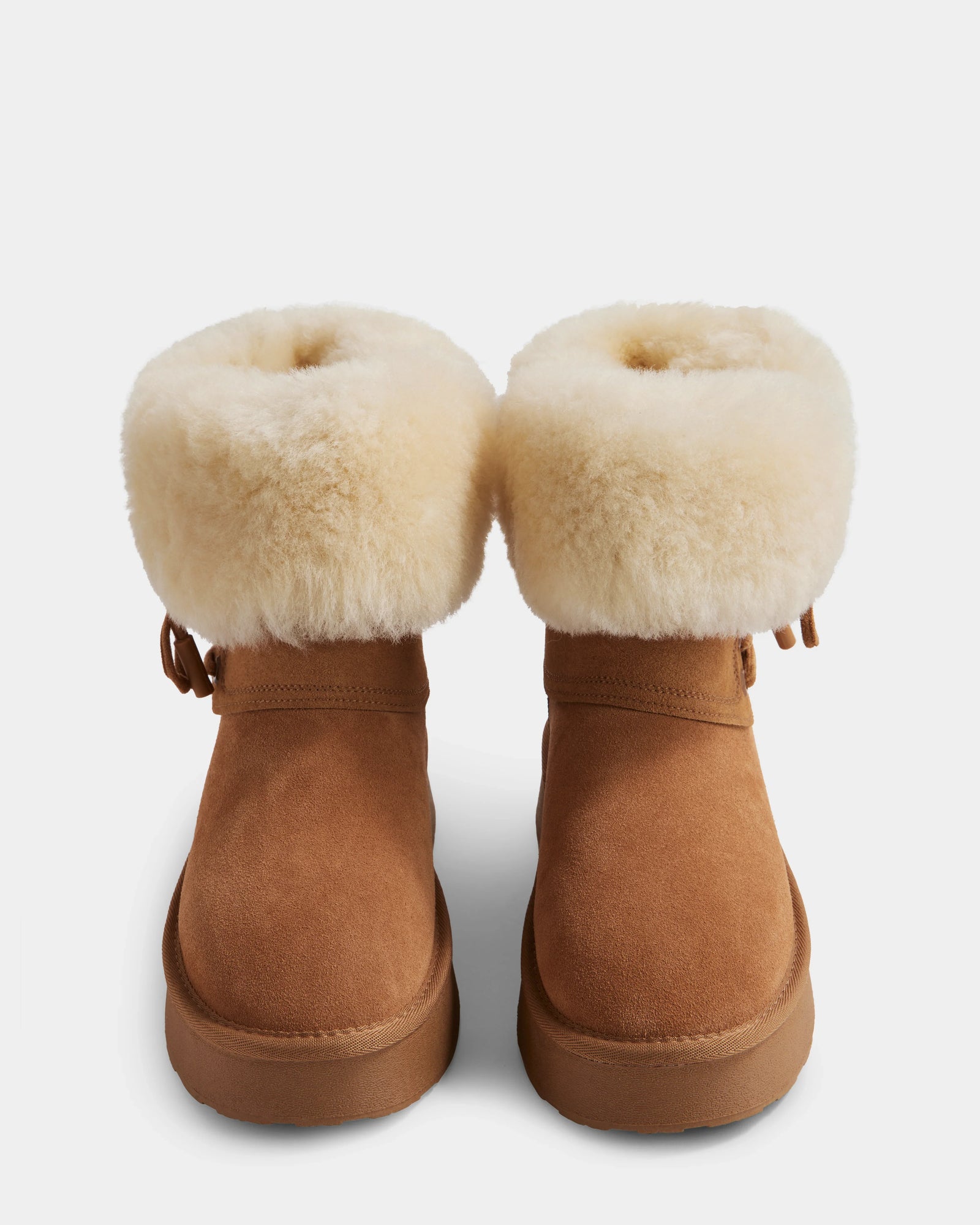 The Rudsak INESA - L225026 Tan boots are cozy women’s suede platform boots with thick light beige shearling cuffs and soft wool lining, shown from the front against a white background.