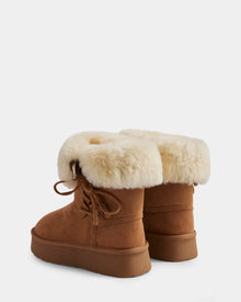 The INESA - L225026 Tan by Rudsak are women’s brown suede platform ankle boots with tan rubber soles and folded-over wool-lined cuffs. One cozy winter boot faces forward, the other is angled slightly back.