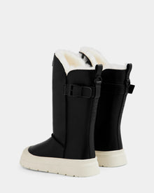 The Rudsak KLAIR L - L225519 Black women’s leather boots feature white soles, cozy fleece lining, side buckles, and a high-top design. Shown from the back and side angles against a plain light background.